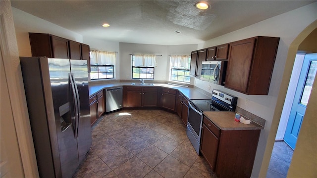 kitchen with light tile patterned floors, stainless steel appliances, sink, and kitchen peninsula