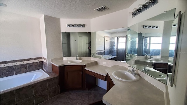 bathroom with vanity, a textured ceiling, plus walk in shower, and tile patterned flooring