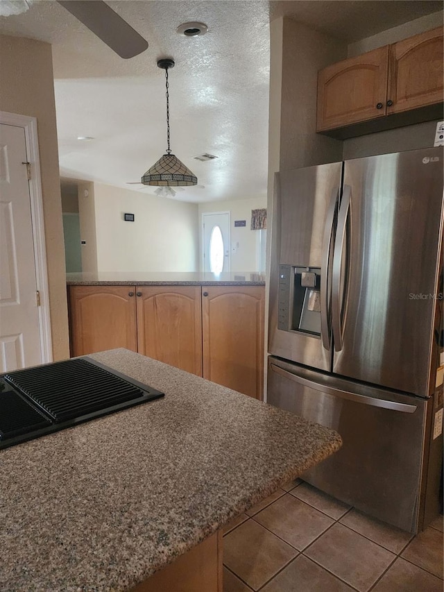 kitchen with a textured ceiling, light tile patterned flooring, pendant lighting, and stainless steel fridge