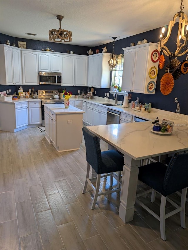 kitchen featuring stainless steel appliances, a kitchen island, hanging light fixtures, a breakfast bar, and light hardwood / wood-style flooring