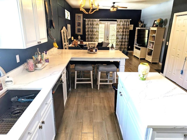 kitchen featuring dark hardwood / wood-style flooring, light stone counters, dishwasher, sink, and white cabinetry