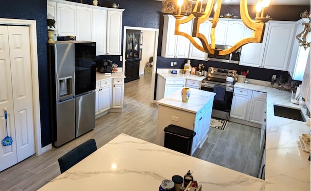 kitchen with light wood-type flooring, white cabinets, a center island, and stainless steel appliances