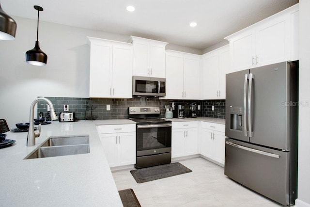 kitchen featuring pendant lighting, tasteful backsplash, sink, stainless steel appliances, and white cabinets