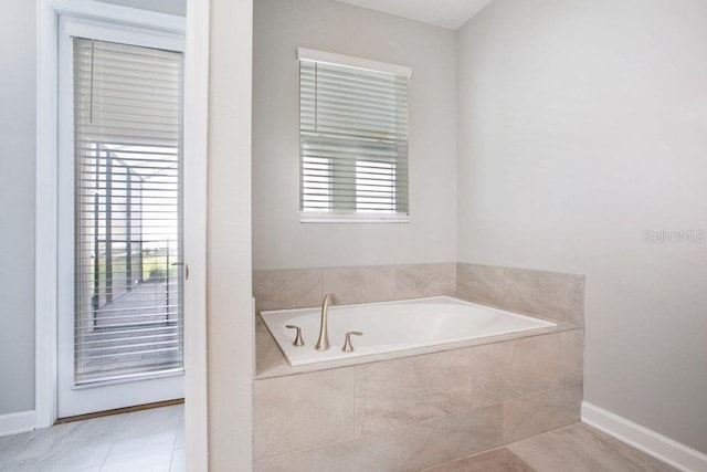 bathroom with tile patterned flooring, plenty of natural light, and a relaxing tiled tub