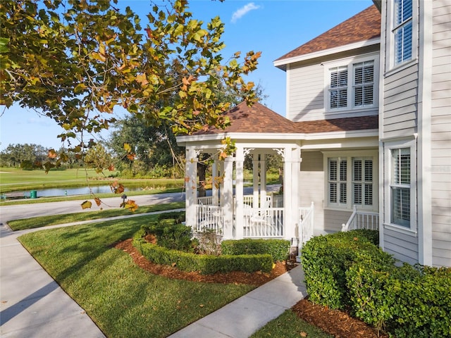 view of yard with a water view and covered porch