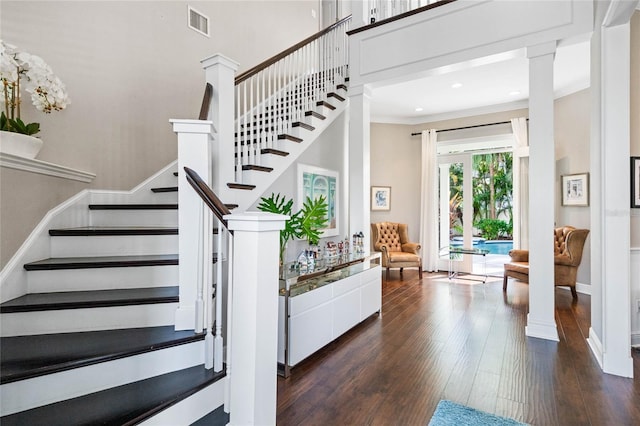 stairway with ornate columns, crown molding, and wood-type flooring