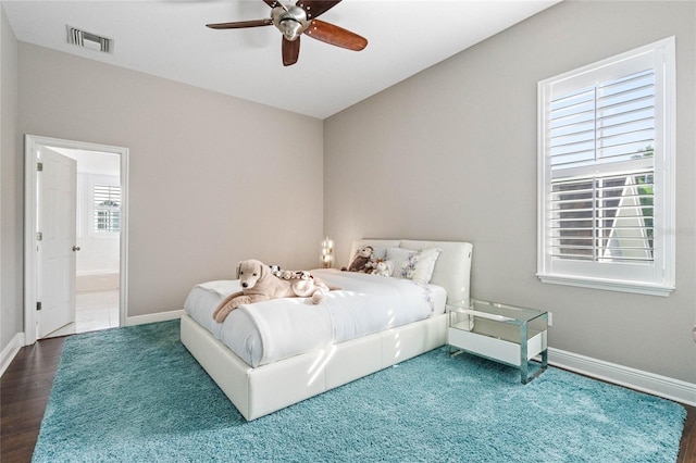 bedroom featuring ensuite bath, hardwood / wood-style flooring, multiple windows, and ceiling fan