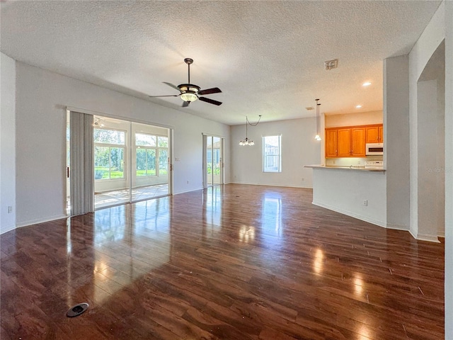 unfurnished living room featuring dark wood-type flooring, a healthy amount of sunlight, and a textured ceiling