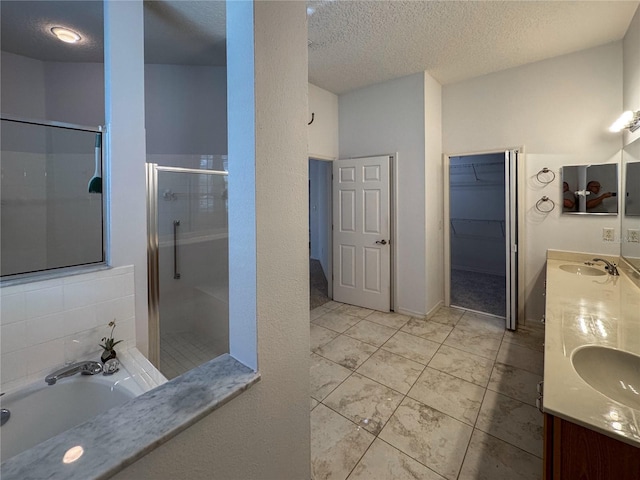 bathroom with vanity, a textured ceiling, and shower with separate bathtub