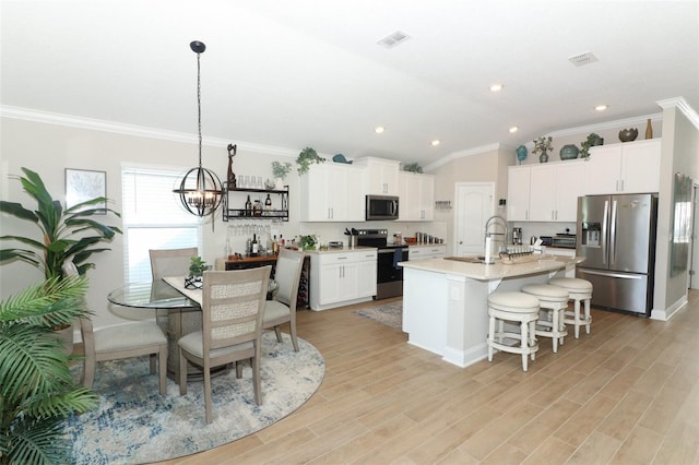 kitchen featuring a kitchen island with sink, white cabinetry, vaulted ceiling, light hardwood / wood-style flooring, and appliances with stainless steel finishes