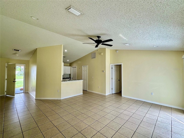 unfurnished living room featuring ceiling fan, vaulted ceiling, light tile patterned floors, and a textured ceiling