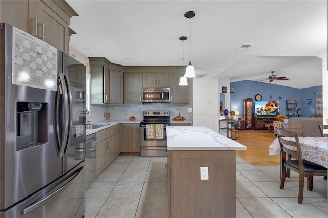 kitchen featuring lofted ceiling, a kitchen island, hanging light fixtures, stainless steel appliances, and ceiling fan