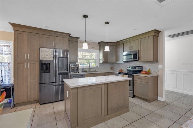 kitchen featuring a center island, light tile patterned flooring, pendant lighting, appliances with stainless steel finishes, and light stone counters