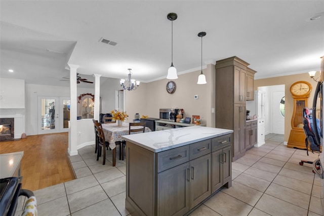 kitchen with crown molding, light stone counters, decorative light fixtures, and decorative columns