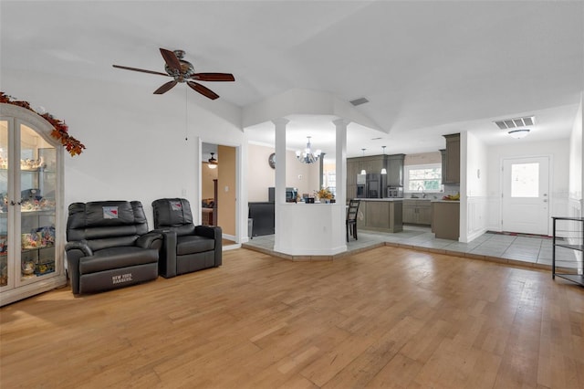 living room featuring sink, ceiling fan with notable chandelier, light wood-type flooring, and vaulted ceiling