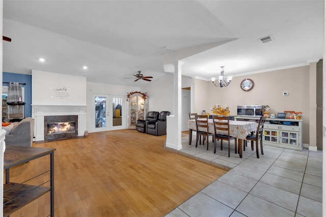 dining room featuring light wood-type flooring, decorative columns, ceiling fan with notable chandelier, crown molding, and french doors