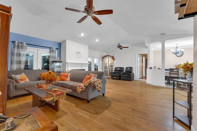 living room with vaulted ceiling, ceiling fan with notable chandelier, and light hardwood / wood-style floors