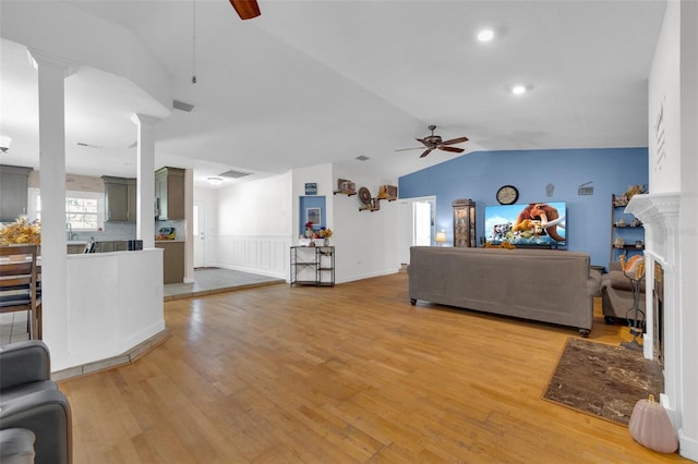 living room with light hardwood / wood-style floors, vaulted ceiling, and ceiling fan