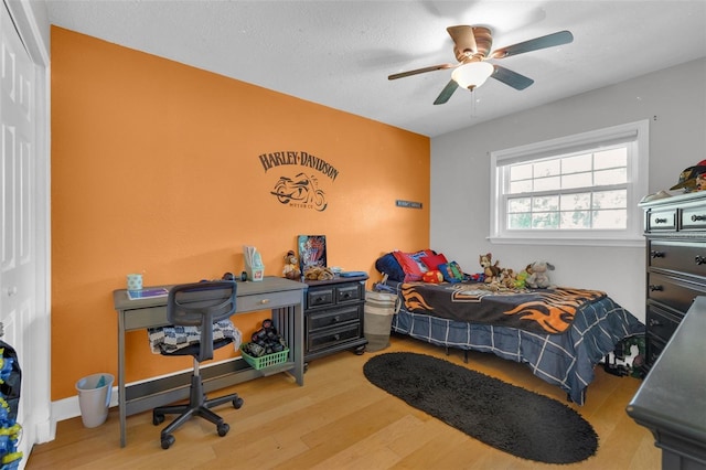 bedroom with a closet, a textured ceiling, wood-type flooring, and ceiling fan