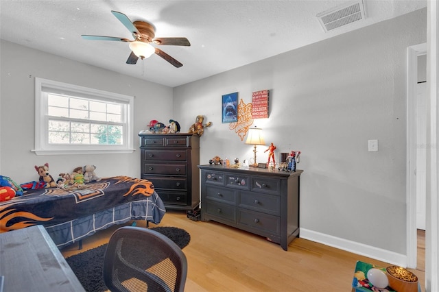 bedroom featuring light hardwood / wood-style floors, a textured ceiling, and ceiling fan