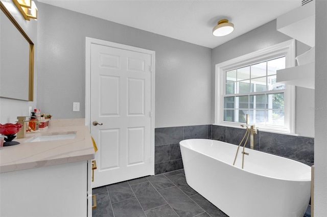 bathroom featuring vanity, a bathing tub, tile patterned floors, and tile walls