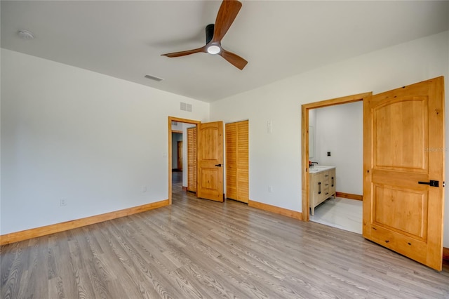 unfurnished bedroom featuring light wood-type flooring, a closet, ensuite bath, and ceiling fan