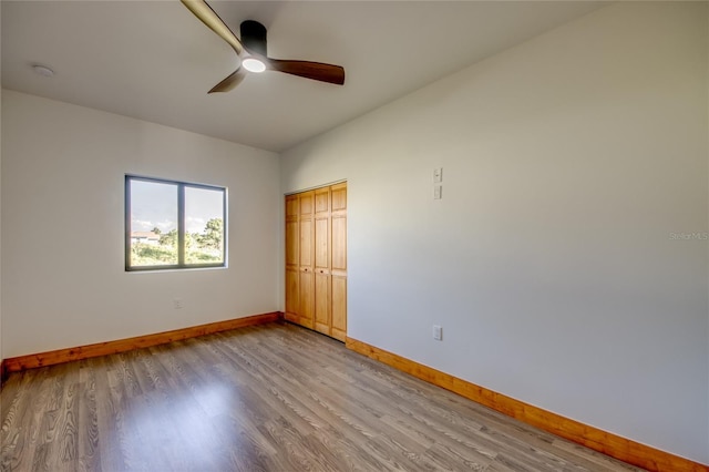 unfurnished bedroom with ceiling fan, a closet, and wood-type flooring