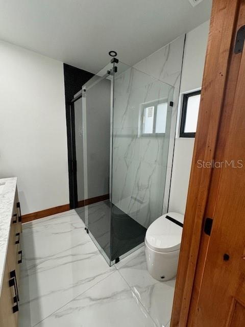 bathroom with a shower with door, vanity, and toilet