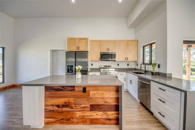 kitchen featuring sink, kitchen peninsula, light hardwood / wood-style floors, light brown cabinetry, and appliances with stainless steel finishes