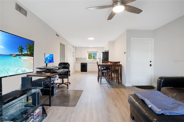 living area featuring light wood-type flooring, visible vents, baseboards, and ceiling fan