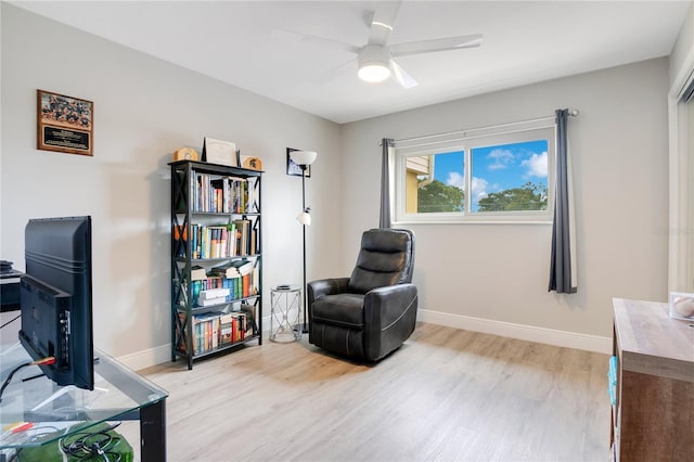 living area with ceiling fan, baseboards, and light wood-style flooring