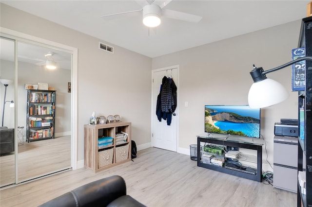 living room with wood finished floors, visible vents, a ceiling fan, and baseboards