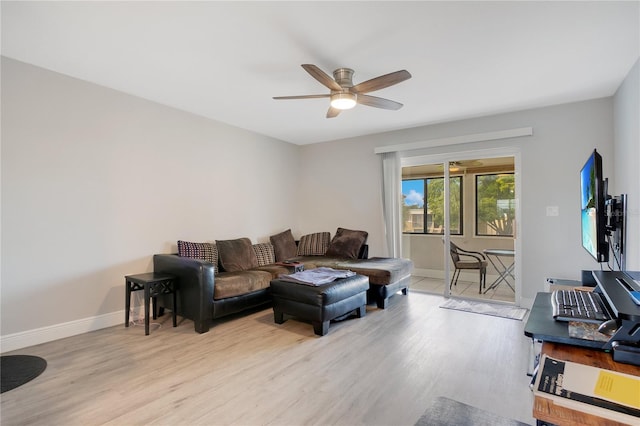 living area with baseboards, a ceiling fan, and light wood-style floors