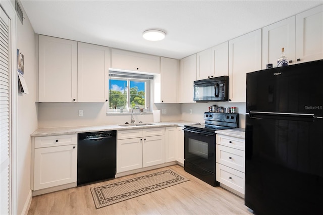 kitchen featuring a sink, black appliances, light wood-style flooring, light countertops, and white cabinetry