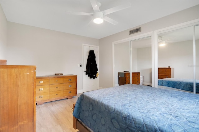 bedroom with a ceiling fan, wood finished floors, multiple closets, and visible vents