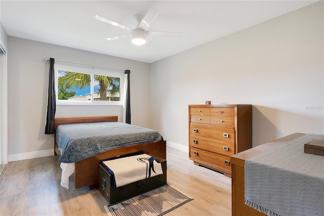 bedroom featuring light wood-style floors, a ceiling fan, and baseboards