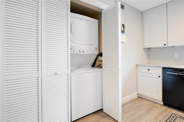 laundry room with baseboards, light wood finished floors, stacked washer / dryer, and laundry area