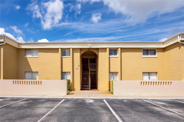 view of building exterior with uncovered parking and fence