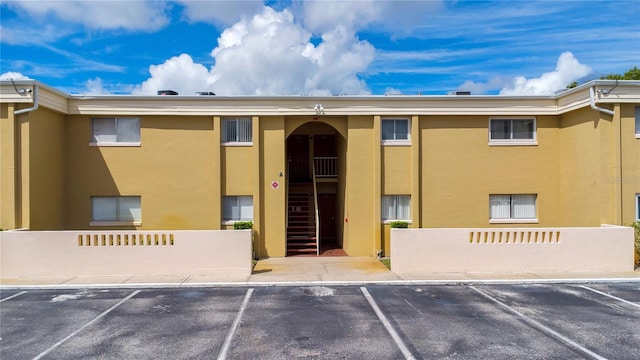 view of building exterior featuring fence and uncovered parking