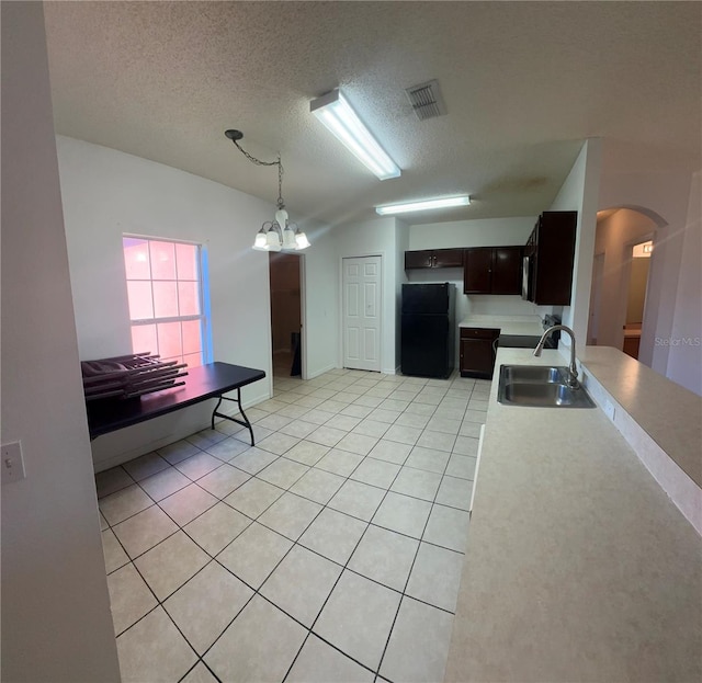 kitchen with light tile patterned flooring, an inviting chandelier, dark brown cabinets, sink, and black refrigerator