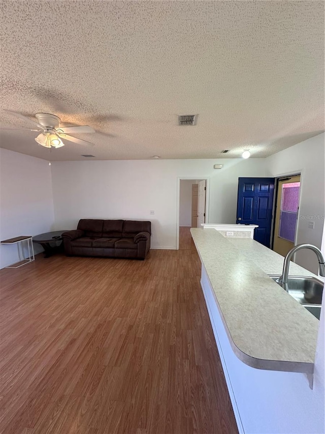 living room featuring a textured ceiling, ceiling fan, sink, and dark hardwood / wood-style flooring