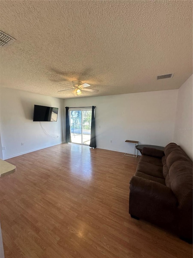 living room with hardwood / wood-style flooring, ceiling fan, and a textured ceiling