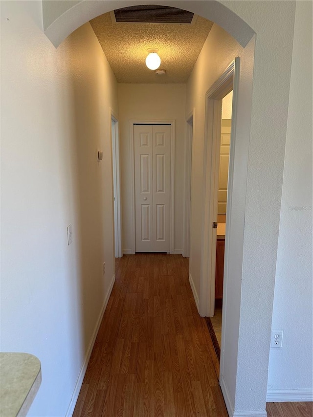 hall with a textured ceiling and dark hardwood / wood-style flooring