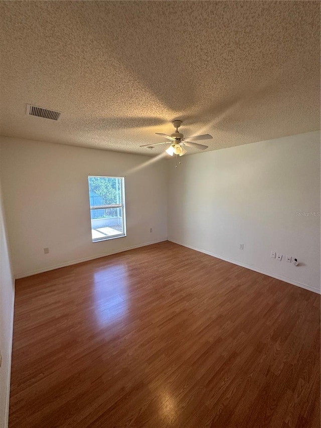 empty room with ceiling fan, dark hardwood / wood-style floors, and a textured ceiling