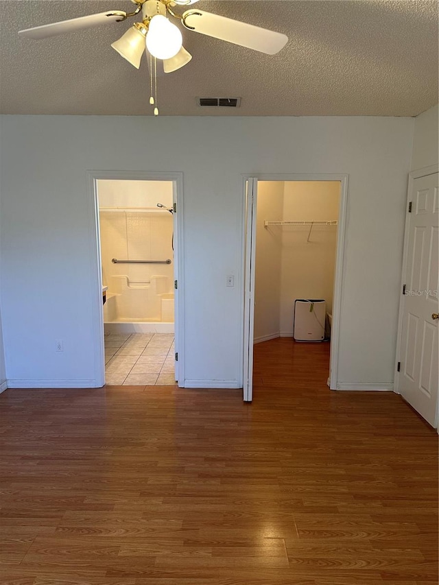 unfurnished bedroom with light wood-type flooring, ceiling fan, a closet, and a textured ceiling