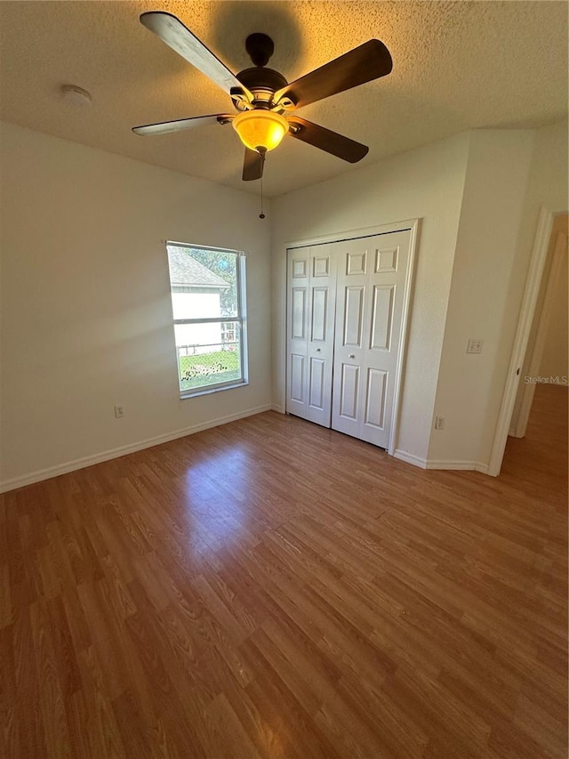 unfurnished bedroom featuring ceiling fan, a textured ceiling, a closet, and hardwood / wood-style floors