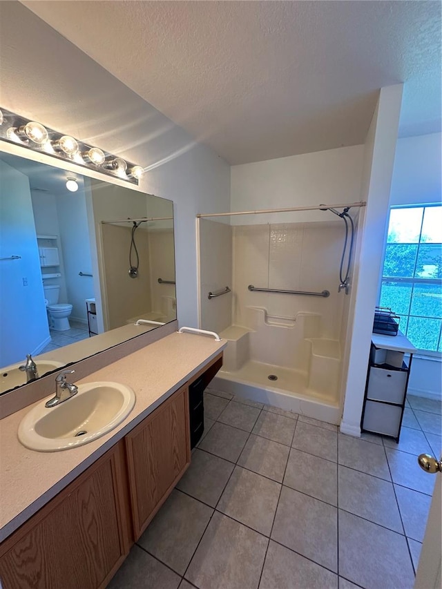 bathroom featuring vanity, tile patterned flooring, toilet, a shower, and a textured ceiling