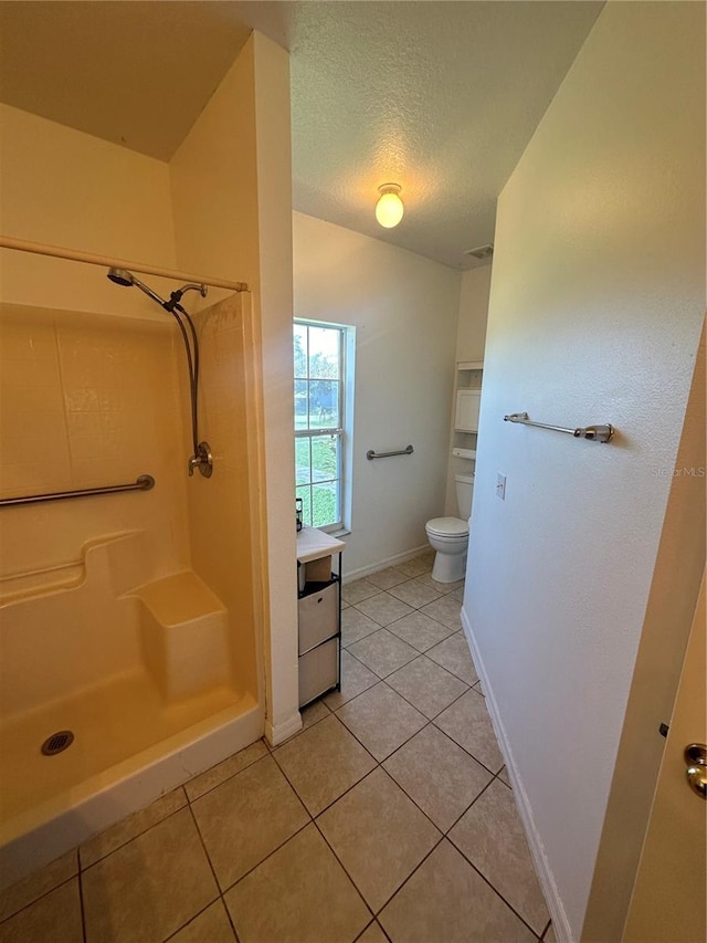 bathroom with tile patterned flooring, walk in shower, toilet, vanity, and a textured ceiling