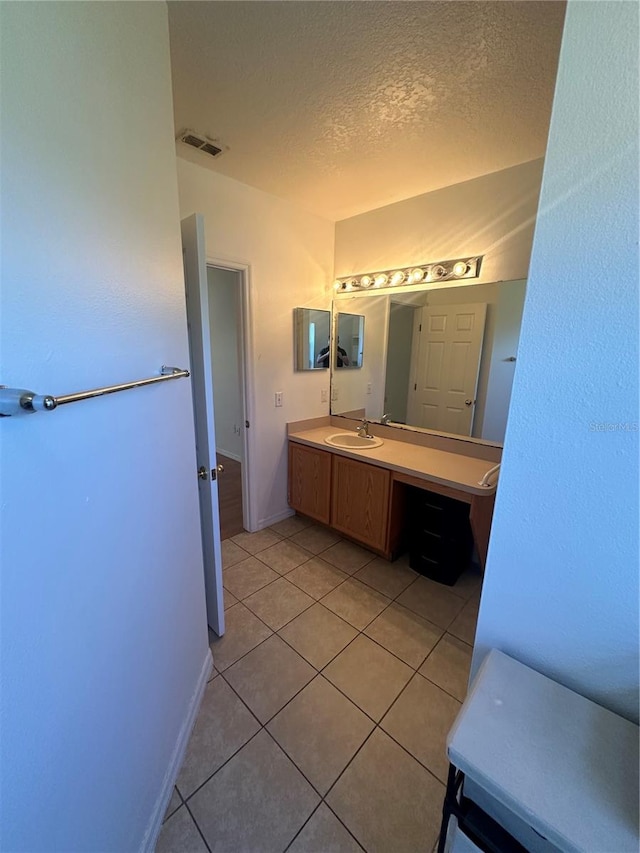 bathroom with tile patterned floors, vanity, and a textured ceiling