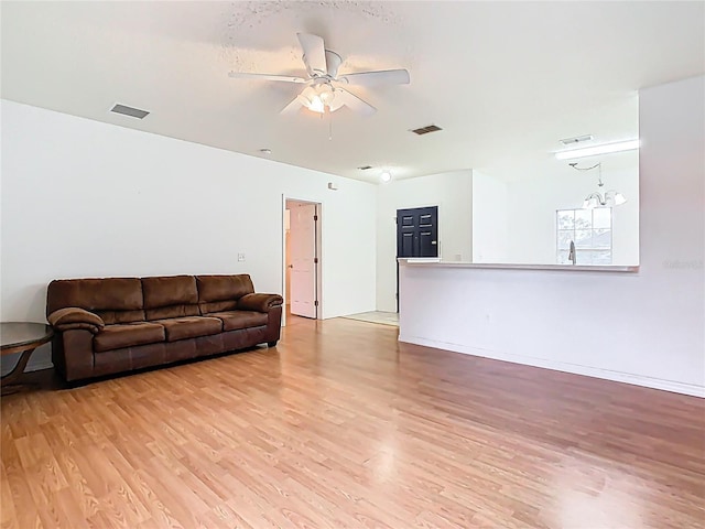 living area featuring visible vents, baseboards, light wood-style flooring, and a ceiling fan